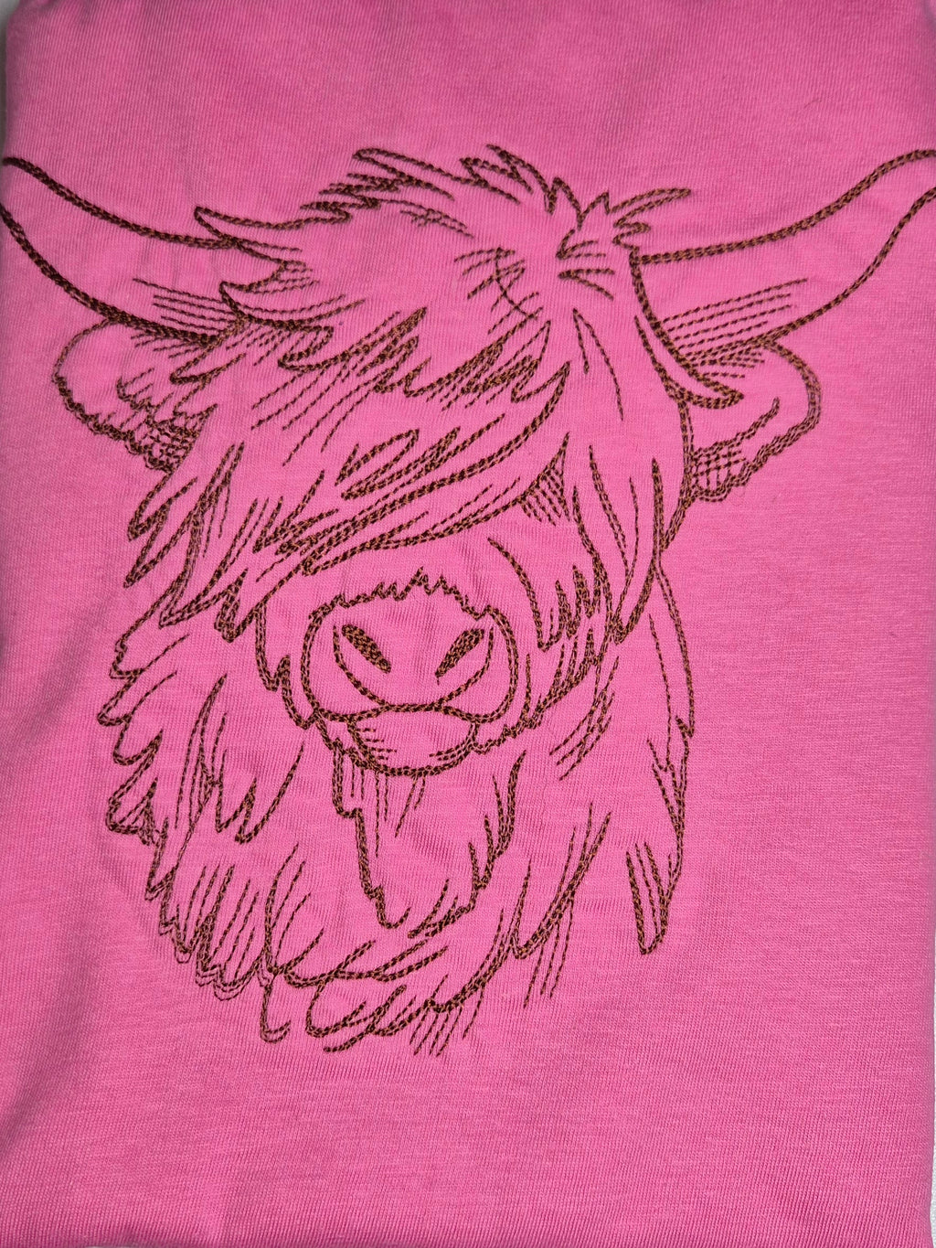 Pink t-shirt with a black embroidered design of a highland cow's head.
